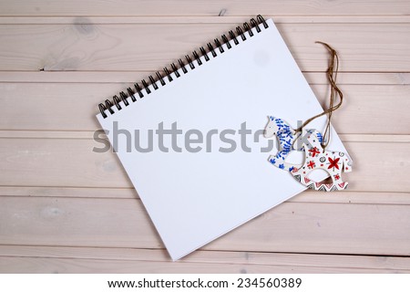 Open white notepad on the wooden table.  Wooden toys folk horses. Mock up  on the wood.
