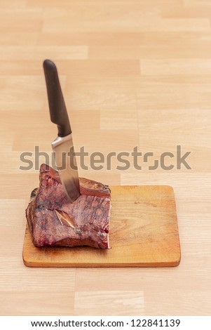 Homemade smoked meat on wooden cutting board with big knife