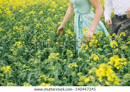 Couple before wedding running in colza field, girl with turquoise dress, without face, vintage color, engagement photo