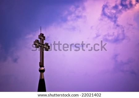 cross at dusk on cloudy purple sky
