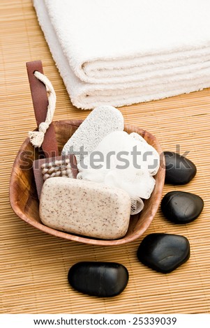 massage stones soap body brush and towel on bamboo board