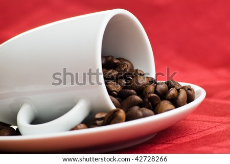 coffee beans in cup on red with shallow depth of field