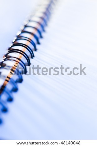 close-up of business spiral notebook with a pen in blue light