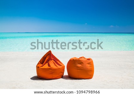 Two  orange pellet bean filiing ban at mazing vibrant beach with turquoise water on Olhuveli island, Maldives.