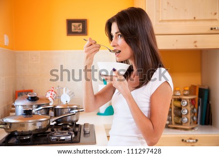 Beautiful young women cooking and testing  the food in the kitchen