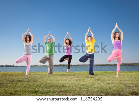 People in group  practice Yoga asana on lakeside. Yoga concept.