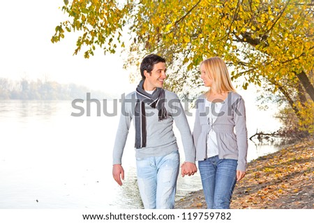 Happy couple in fall under leaves on the river