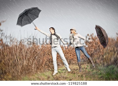 Woman and man with umbrellas during strong storm wind
