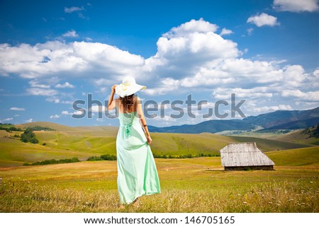 Beautiful young woman with hat in a green dress on the slopes of Zlatibor mountain, Serbia.