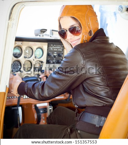Portrait of young beautiful woman pilot in a airplane.