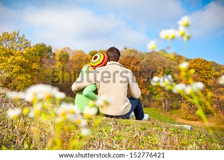 Sweet couple sitting on a hill and looking at the autumn landscape.Autumn set Sweet couple sitting on a hill and looking at the autumn landscape.Autumn set