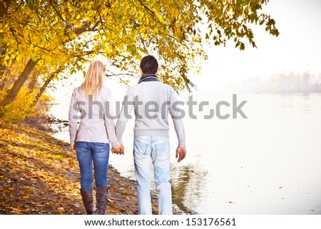 Happy couple have fun under the leaves on the river bank