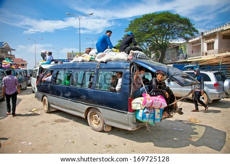 NEAK LEUNG, CAMBODIA - NOV 19, 2013: Passengers sit atop a very overloaded vehicle in Neak Leung on Noveber 17, 2013, Cambodia. This kind of domestic transportation carries between 16 to 30 passengers.