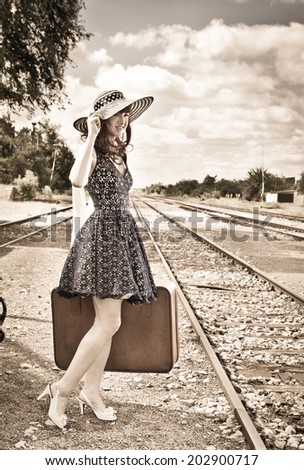 Beautiful woman with  suitcase on a train station. Sepia.