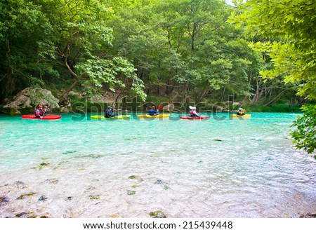 Happy group traveling by kayak on the green waters of Acheron river in Greece.