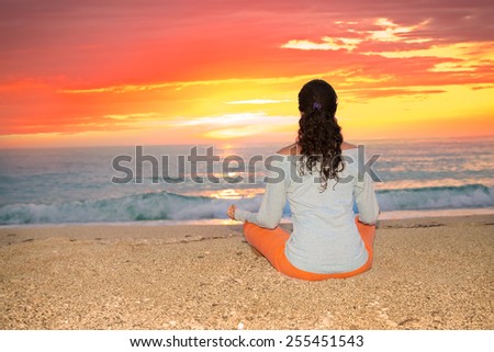 Relaxed sexy young brunette woman sitting on a deserted tropical beach at sunset. Greece.