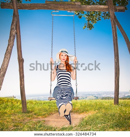 Beautiful girl on the swing under a tree with panoramic view on Vojvodina, Serbia.