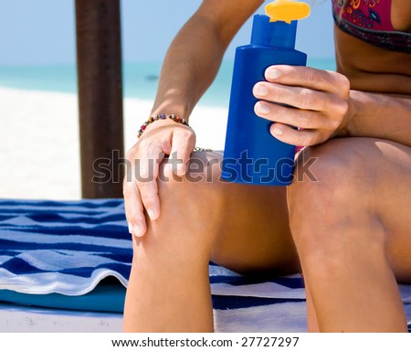 Pretty woman smooth her skin wit suntan lotion at the tropical beach
