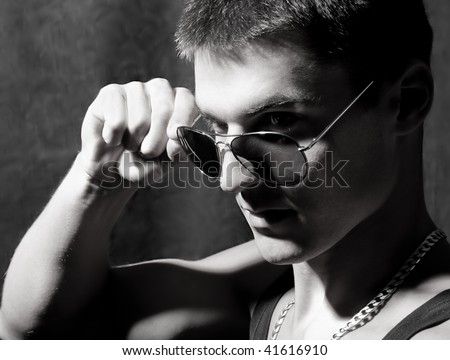 Black and white portrait of trendy attractive man with glasses who is smiling and he has glamorous look