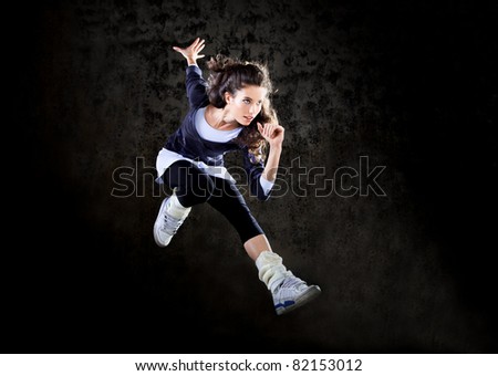 Dancing woman with brown long hair and happy facial expression jumping up.
