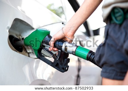woman hand holding fuel nozzle and refuel car in gas station