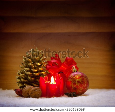 Red christmas decoration and advent candle isolated on wooden background.