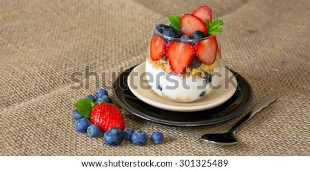 Fresh Yogurt with strawberries and blueberries isolated on brown cloth background.