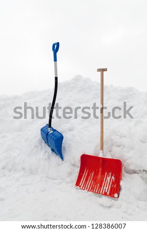 Multicolored snow shovels in snow pile