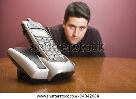 A man looks intently waiting for the phone to ring