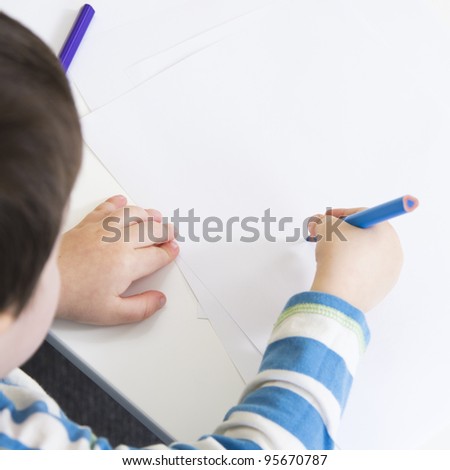 Over shoulder view of a young boy drawing