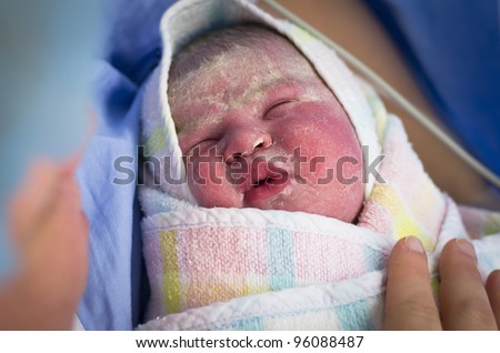 Face of a newborn baby being held by her mother