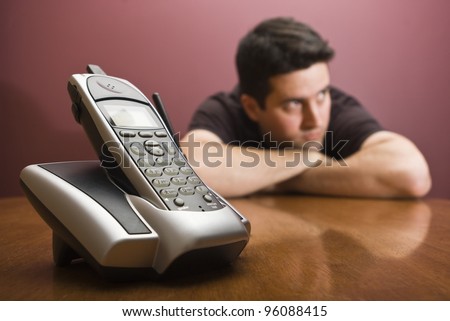 A man is bored waiting for the phone to ring