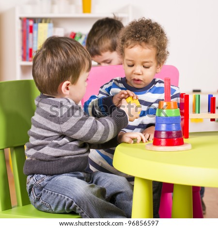 A stock photo of a caucasian and african american child sharing in the play room