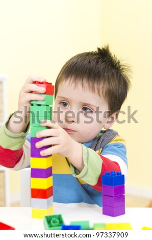 Young boy builds a tower with connecting blocks