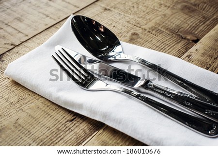 Dinnerware - fork, knife and spoon in napkin on a wooden table