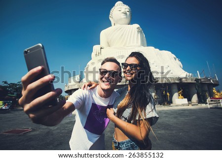 Multiracial couple of students in love smile and make selfie photo with smartphone camera while traveling across Asia on vacation