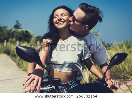 Happy free multiracial couple driving scooter in tropical forest on summer vacation while travel. Young man and woman enjoy the honeymoon.