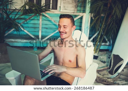 Happy business man working freelance using laptop at the beach house of a tropical island