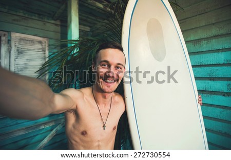 A young hipster surfer making selfie with his surf at beach house at ocean side