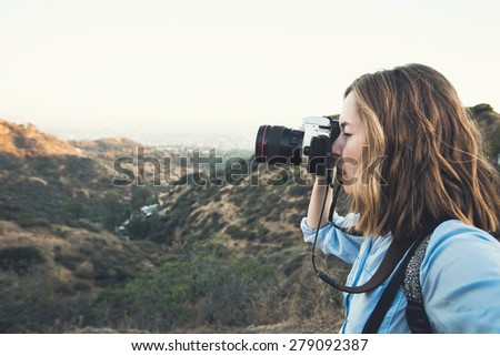 Beautiful young woman photographer hiker taking selfie on the top of a mountain peak at Hollywood hills when hiking and shooting