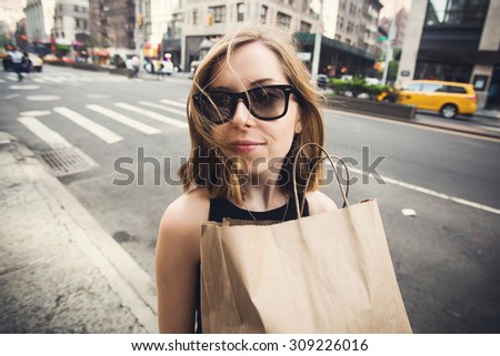Woman doing shopping on Manhattan, New York City having fun laughing outside in streets of New York in summer day. Beautiful caucasian teenage girl holding shopping bag.