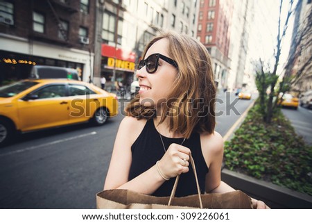 Woman doing shopping on Manhattan, New York City having fun laughing outside in streets of New York in summer day. Beautiful caucasian teenage girl holding shopping bag.