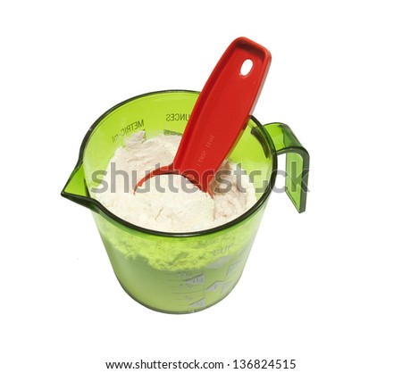 green measuring cup with flour and 1 tbsp measuring spoon on a white background