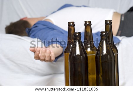 Businessman passed out on the couch. Empty beer bottles.