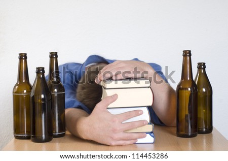 Young student passed out behind books. Surrounded by empty beer bottles.