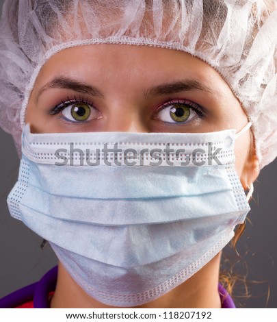 Portrait of a woman doctor wearing mask and cap - on grey background