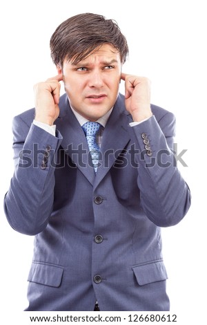 Young businessman with fingers in his ears  protecting himself from noise on white