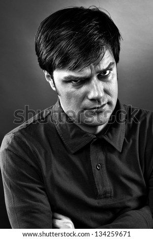 Monochrome closeup portrait of a young man with grumpy expression