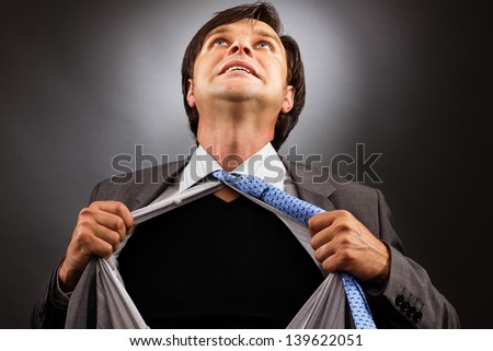 Business man tearing off his shirt over gray background