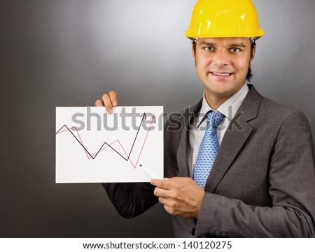 Young engineer drawing a rising graph, representing business growth on gray